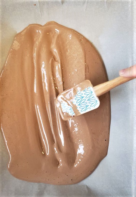 Spreading chocolate cake batter with a spatula.