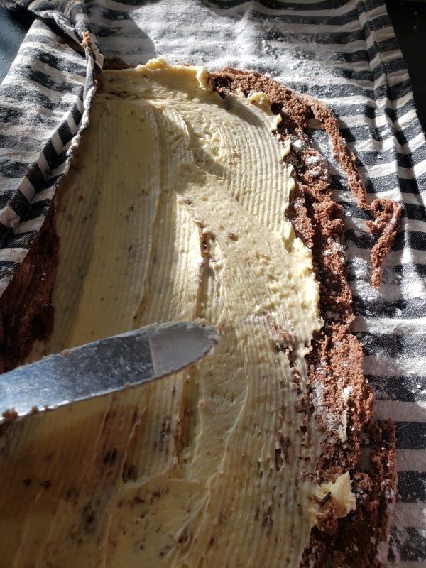 Spreading frosting on a chocolate roll cake.