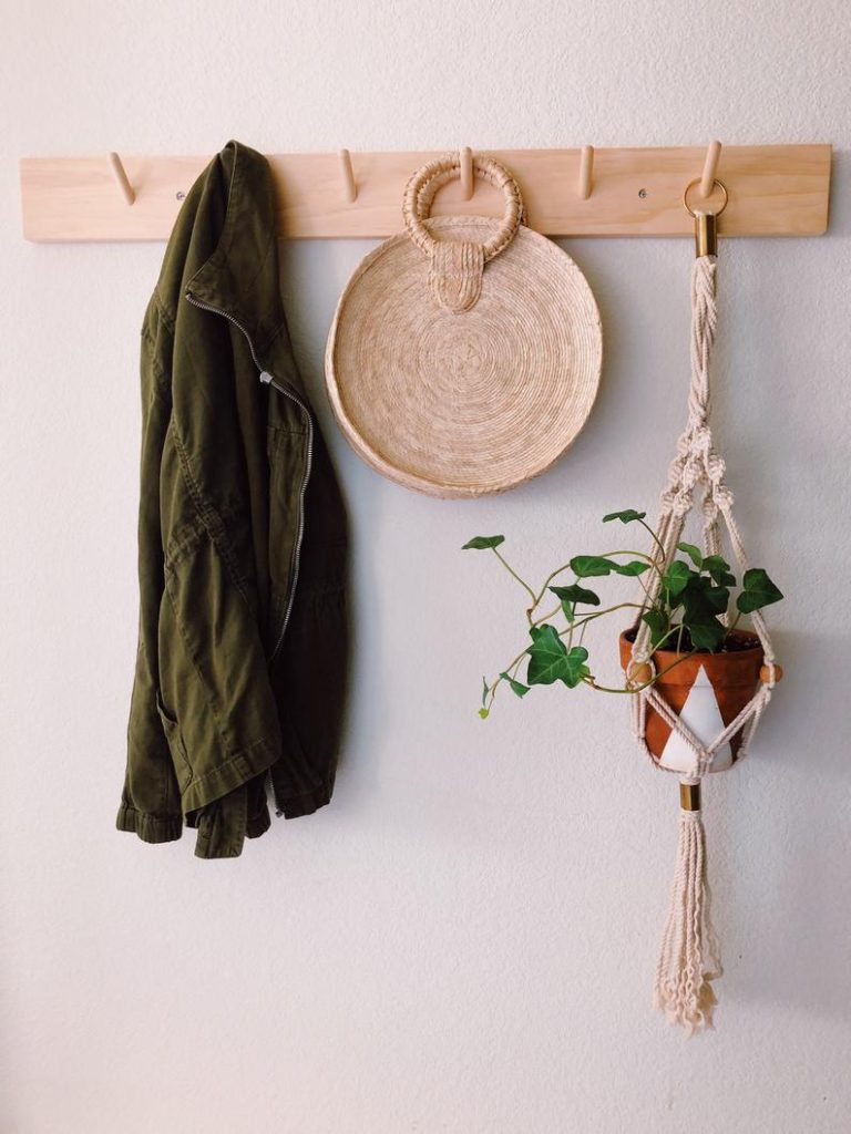 Natural wood peg rail with a green coat