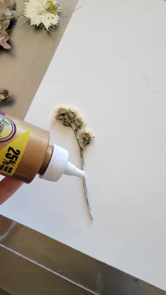 adding glue to pressed flower