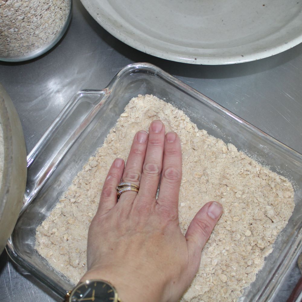 pressing crumb mixture in a 9 by 9 inch pan