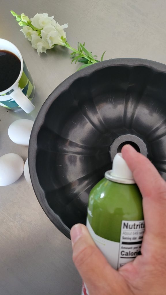 Spraying a bundt pan with Canola oil spray.