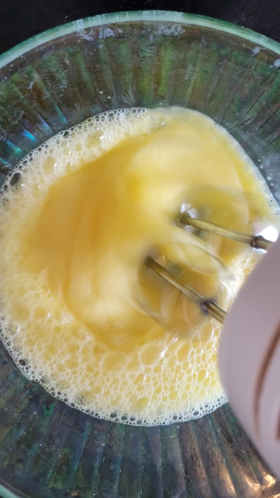 Eggs being beaten in a glass bowl.